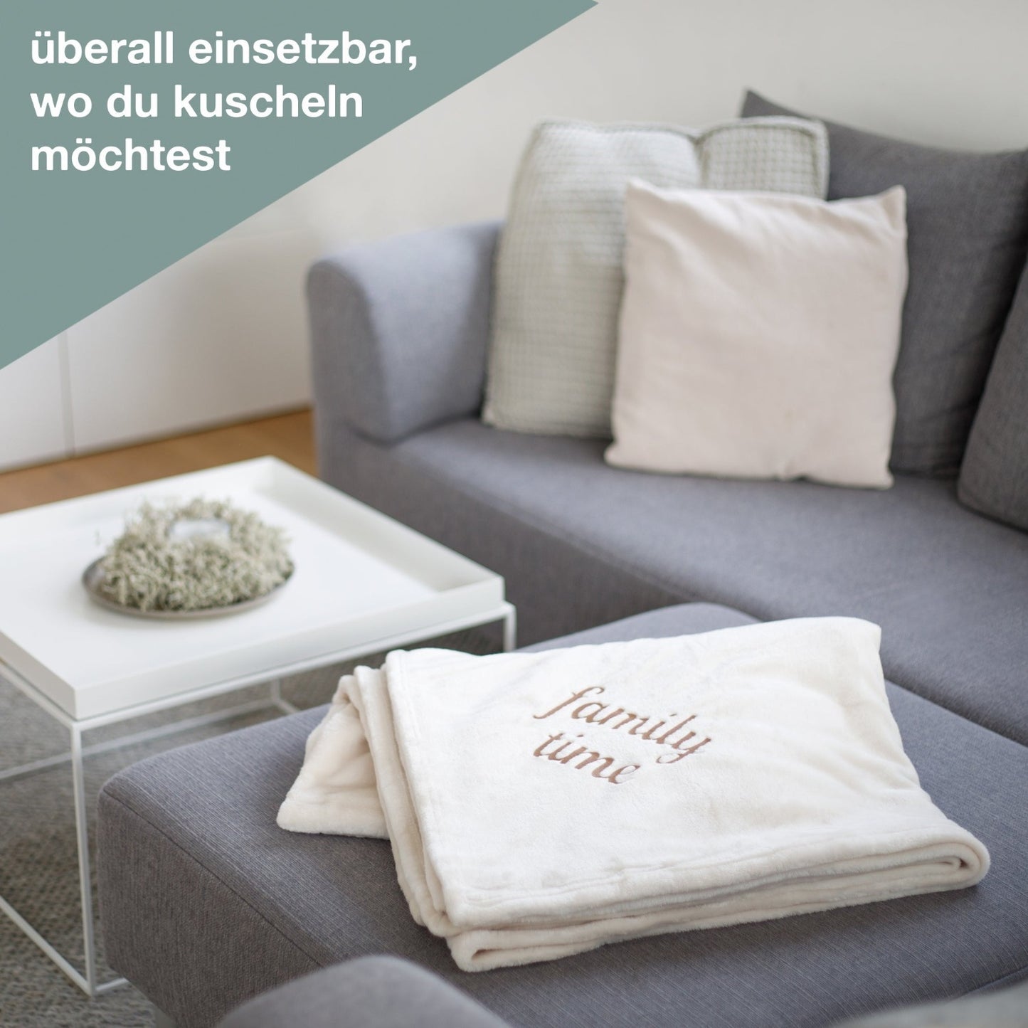 Kuscheldecke beige mit family time bestickt liegt auf dem Sofa von wolimbo