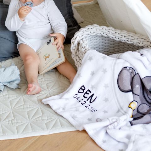 Kleinkind mit bestickter Babydecke