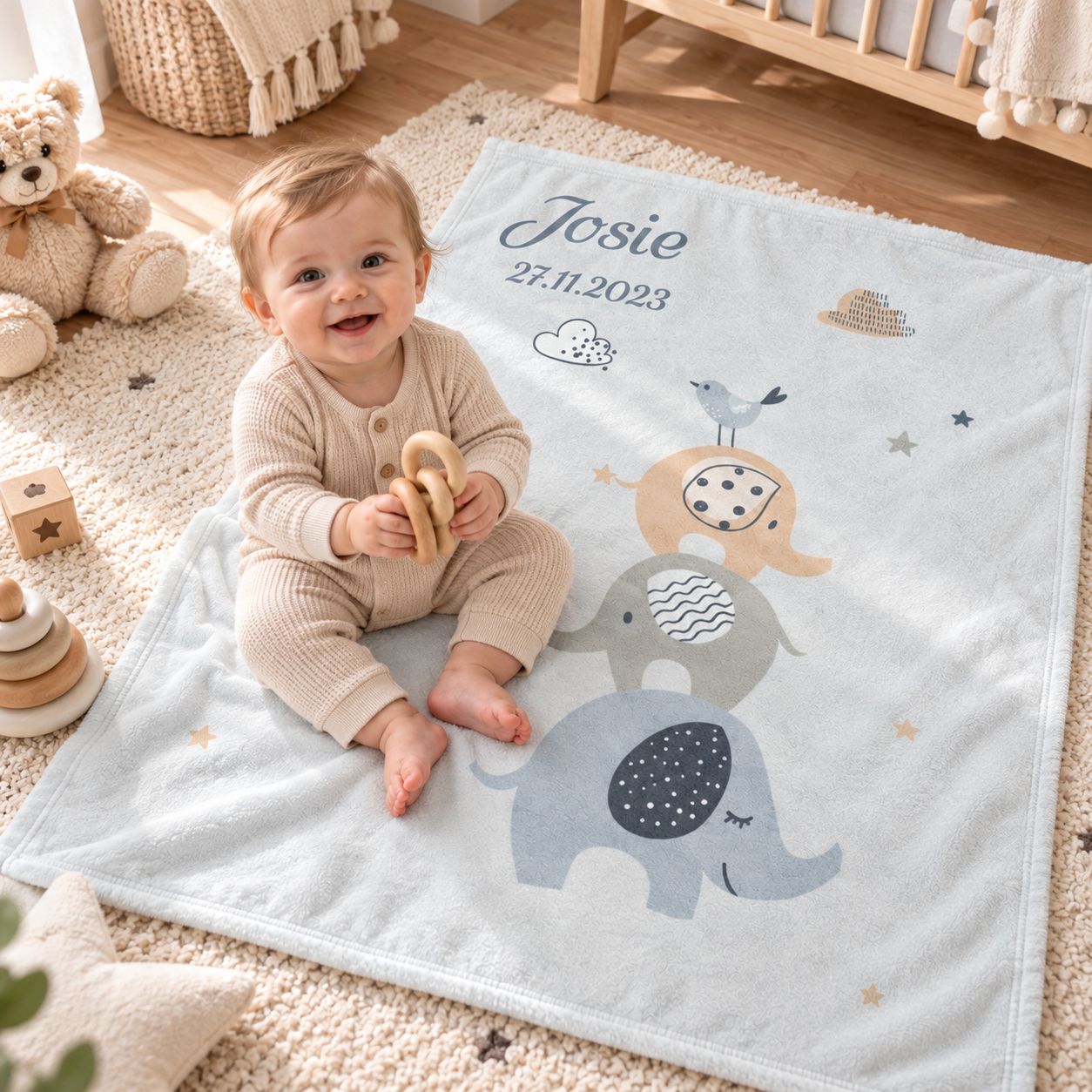 Baby sitzt auf personalisierter Babydecke mit Namen und Elefantenmotiv