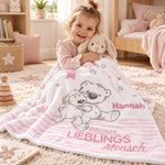 Mädchen kuschelt mit personalisierter rosa Babydecke im Kinderzimmer