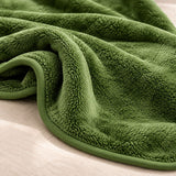 Detailaufnahme der grünen Kuscheldecke mit weichem Flor und Einfassung