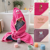 Kind im pinken Kapuzenhandtuch mit Namen sowie verschiedene Farben und Stickmotive