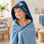 Kind mit dunkelblauem Kapuzenhandtuch, Elefantenmotiv und Namen im Badezimmer