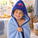 Junge mit personalisiertem Kapuzenhandtuch mit Feuerwehrmotiv in Blau nach dem Baden
