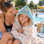 Kind im personalisierten Kapuzenhandtuch mit Namen und Igelmotiv am Schwimmbad