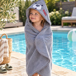 Kind am Pool eingehüllt in graues Kapuzenhandtuch mit Seehund-Motiv und Namen