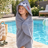Kind am Pool eingehüllt in graues Kapuzenhandtuch mit Seehund-Motiv und Namen