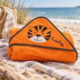 Orangefarbenes Kapuzenhandtuch mit Tigermotiv und gesticktem Namen Lutz am Strand