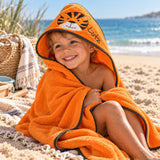 Kind am Strand mit orangefarbenem Kapuzenhandtuch, Tigermotiv und gesticktem Namen Lutz