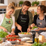 Drei Freunde beim gemeinsamen Kochen mit individuell bestickten Kochschürzen