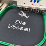 Kochschürzenstoff in einer Stickmaschine mit weißer Motiv- und Schriftstickerei
