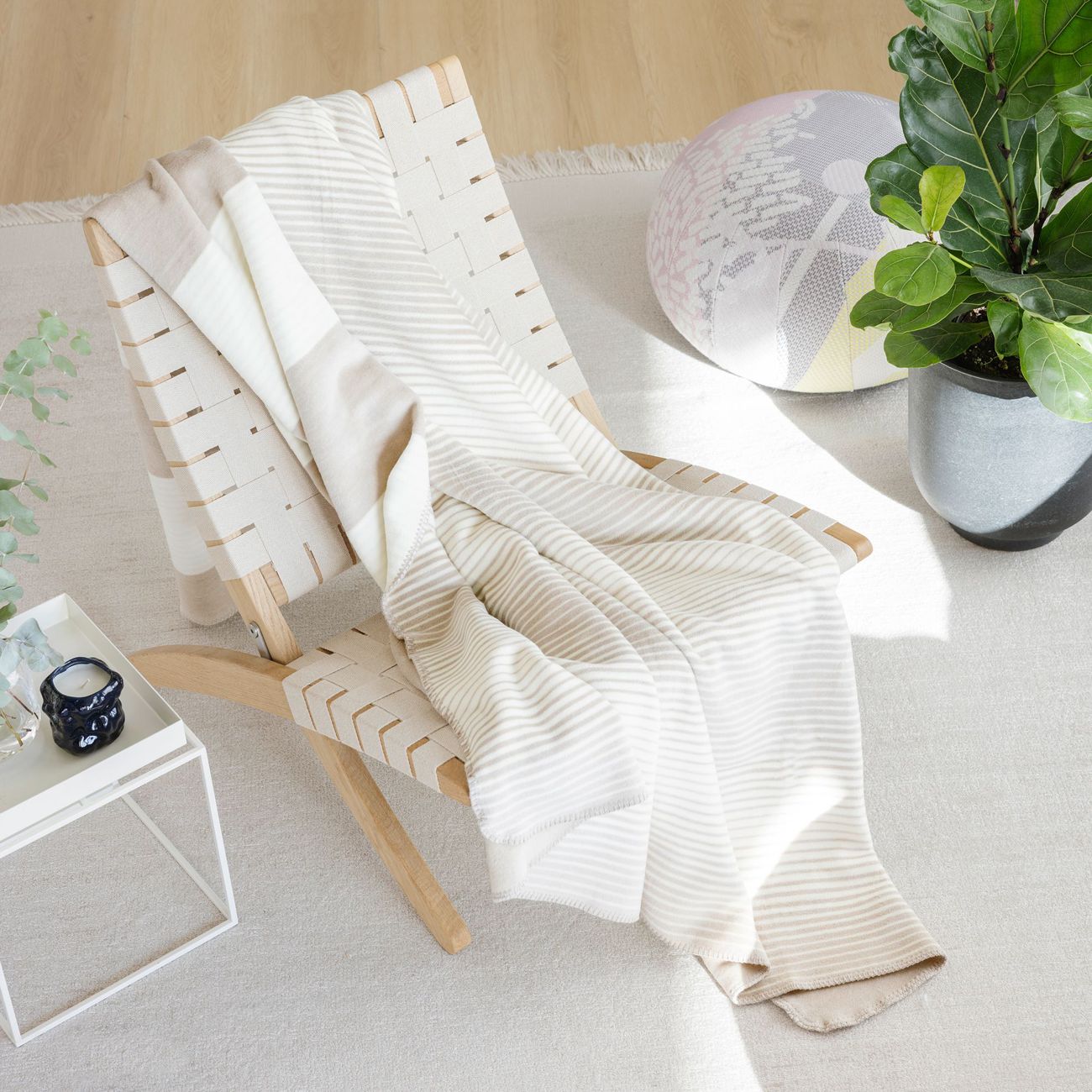 Beige-weiß gestreifte Wohndecke dekorativ über einem Sessel im Wohnzimmer