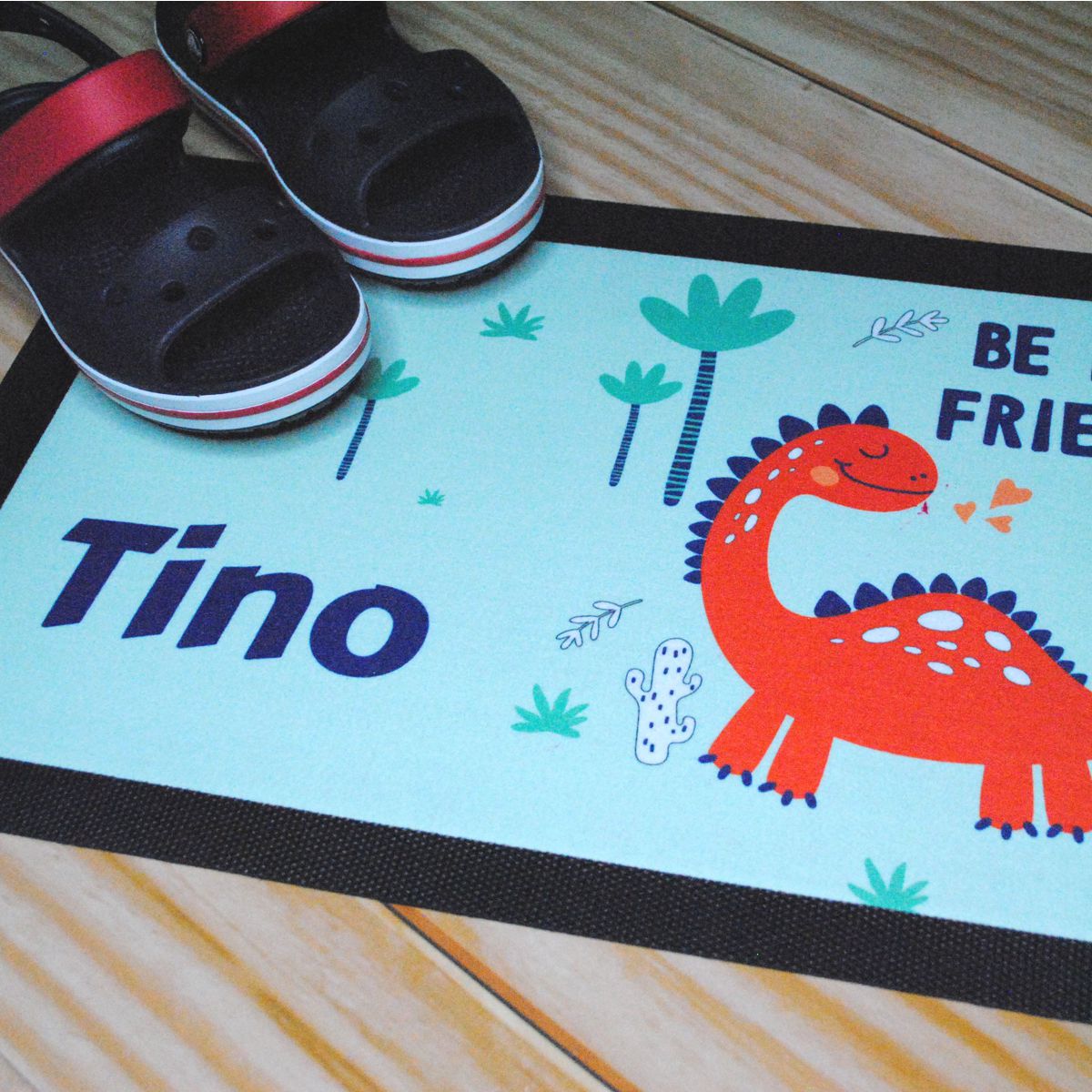 Beispiel Fußmatte Dino-Motiv mit Namen und Schuhe auf Fußboden
